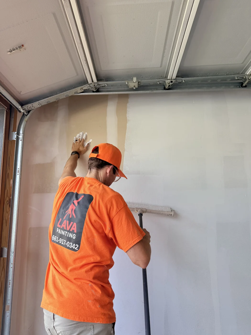 A crew member working on a wall with adjacent surfaces masked. This is a residential project example, not a completed commercial job.