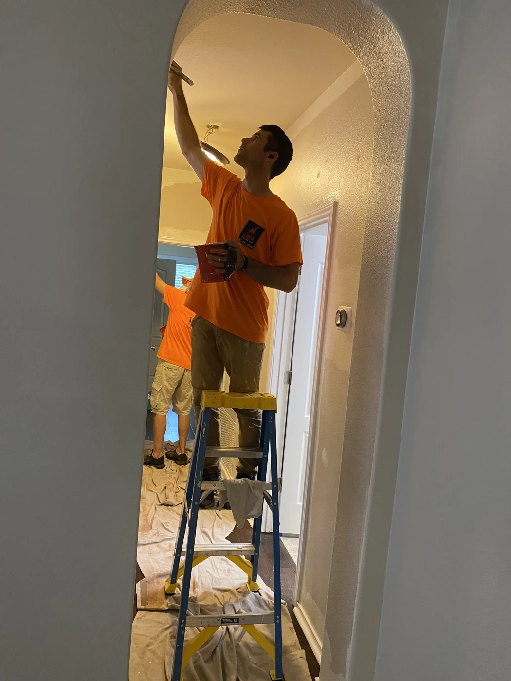 A painter works from a ladder in a residential interior. Access requirements for a commercial property are assessed separately.