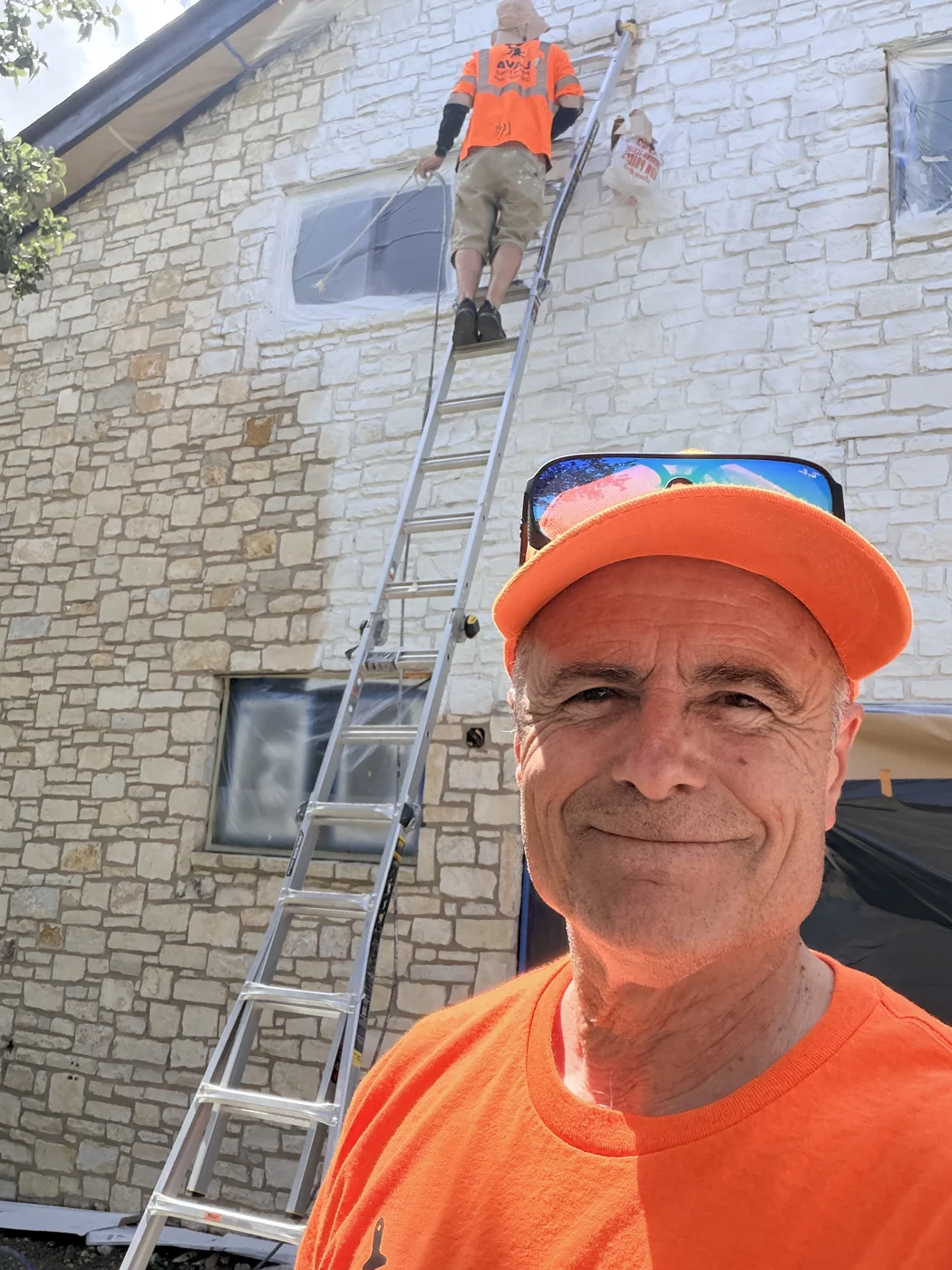 A Lava Painting crew member on an exterior project, with another working from a ladder.