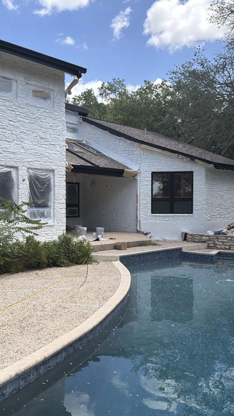 A view across the pool toward a white exterior and contrasting dark roofline.