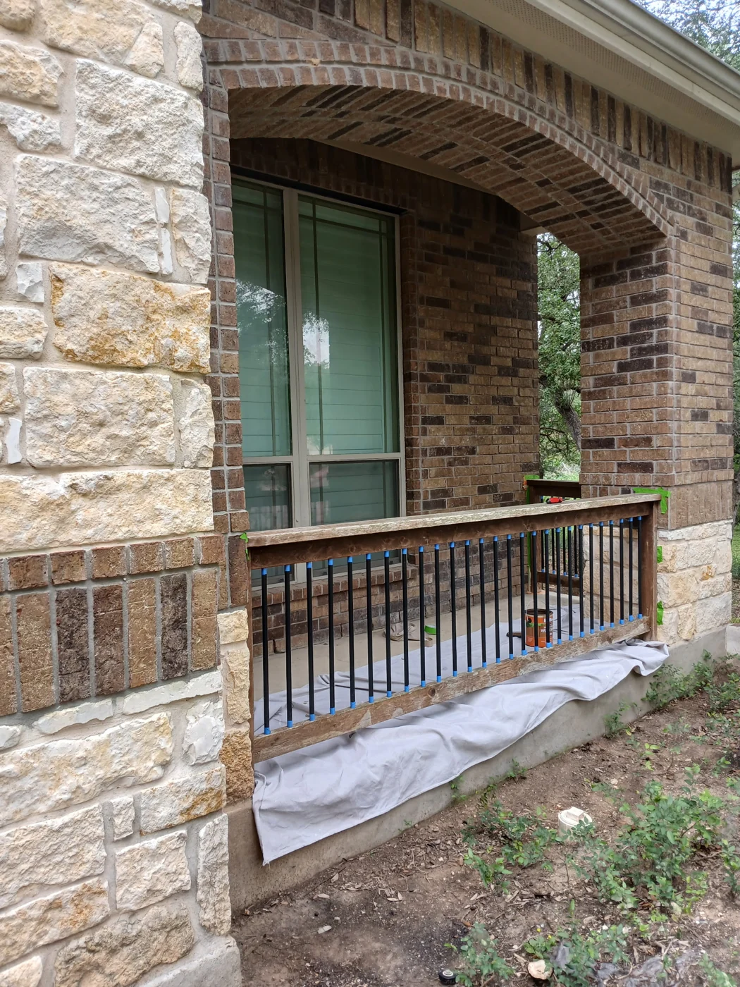 A view of a deck railing alongside the stone exterior of a home.