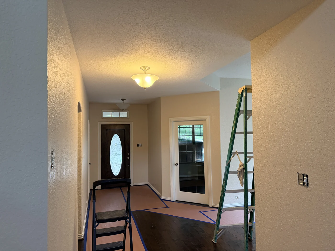 A hallway and entryway during interior work, with access equipment in place.