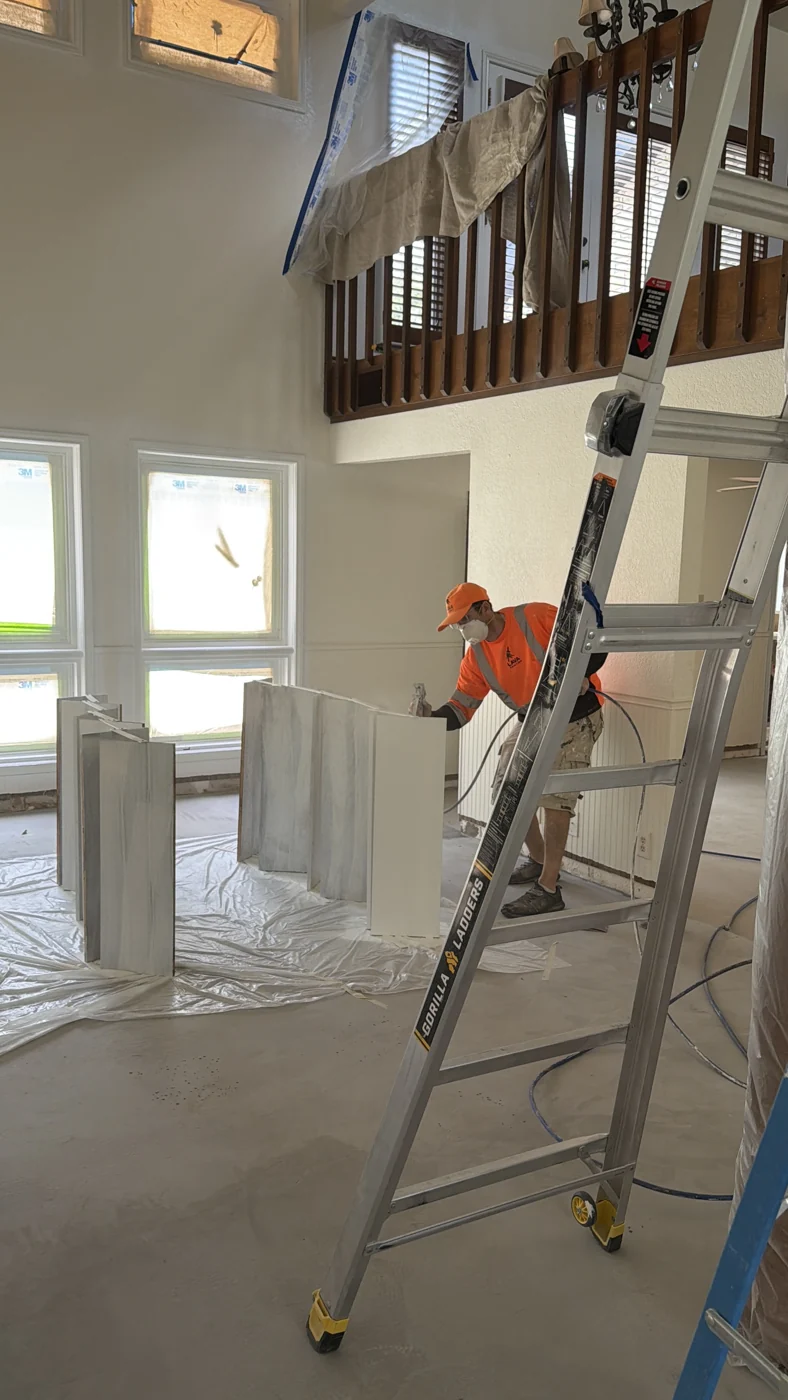 A crew member works in a tall living area with nearby surfaces masked and protected.