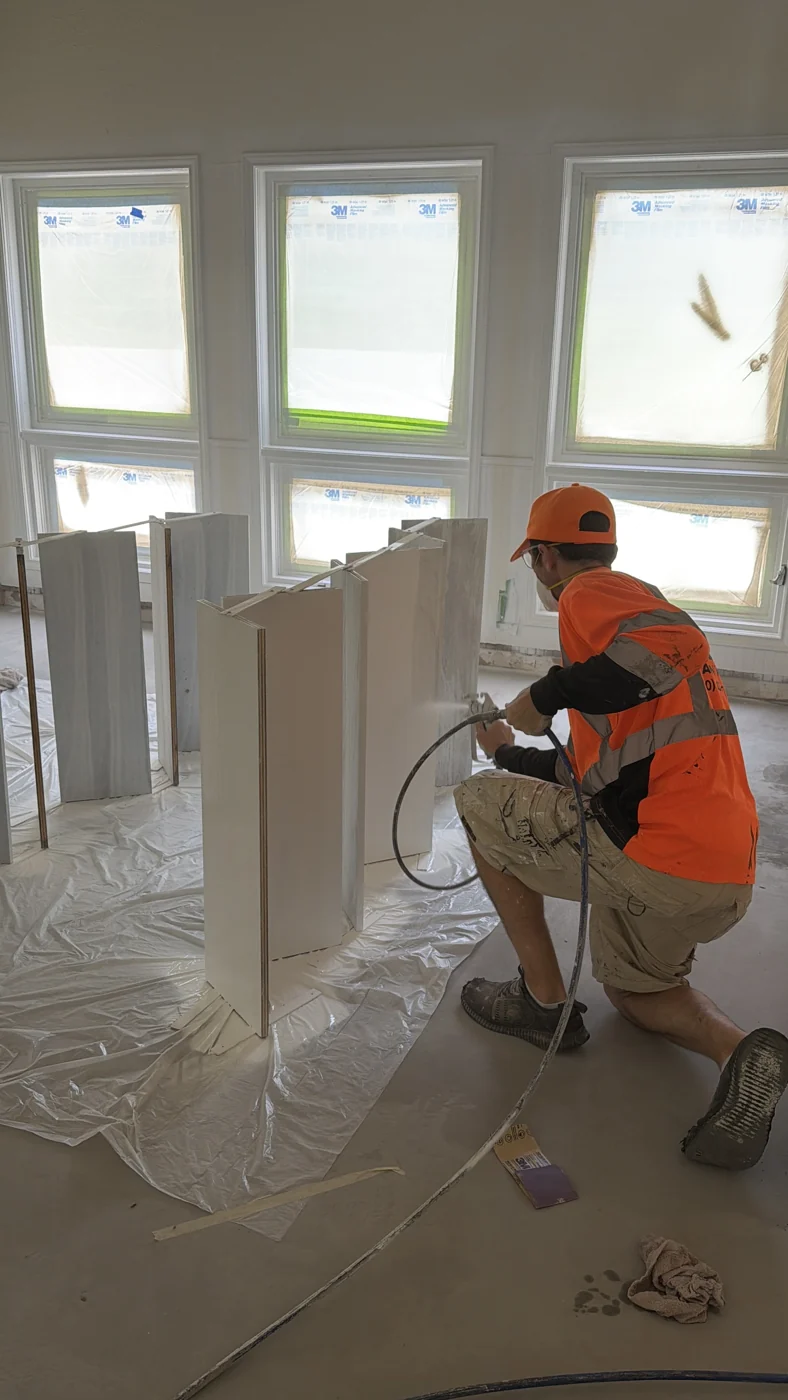 Interior painting in progress beside protected windows and surrounding surfaces.